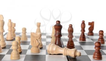 Chess pieces on game board against white background 