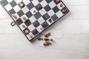 Game board with chess pieces on white wooden table 