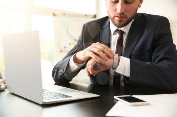 Businessman looking at his watch in office�