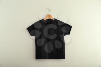 Hanger with blank black t-shirt on light background�