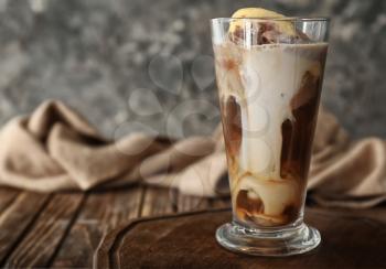 Glass of cold coffee with ice cream on wooden table�