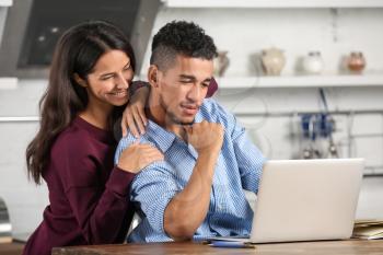 Young couple with laptop in kitchen�