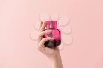 Woman holding bottle of perfume on color background�