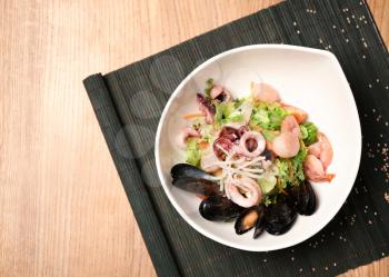 Plate with tasty seafood salad on table�