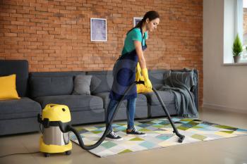 Female janitor hoovering carpet in flat�