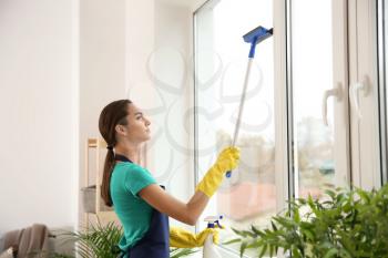 Female janitor cleaning window in flat�
