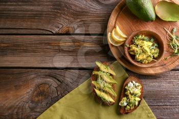Composition with delicious avocado toasts on wooden table, top view�