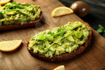 Delicious avocado toasts on wooden board, closeup�