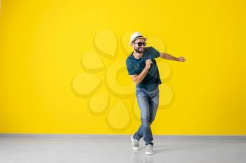 Handsome young man dancing near color wall�