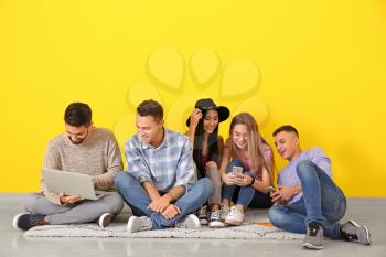 Young students sitting on floor near color wall�