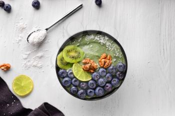 Bowl with tasty spirulina smoothie on white wooden table�