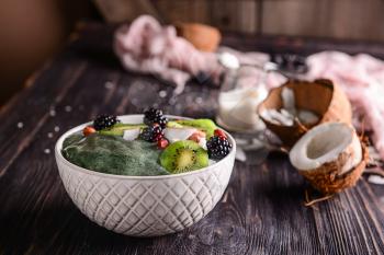 Bowl with tasty spirulina smoothie on dark wooden table�