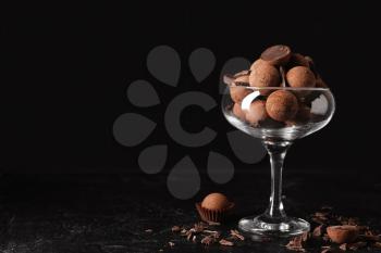 Glass bowl with sweet truffles on dark background�