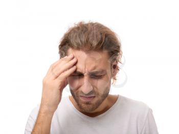 Young man suffering from headache on white background�