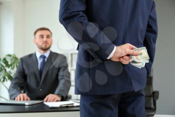 Man hiding bribe for businessman behind back in office. Concept of corruption�