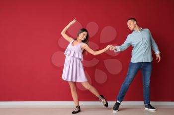Young couple dancing near color wall�