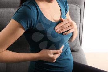 Pregnant woman touching her breast at home�