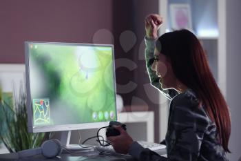 Emotional young woman playing computer game at home�