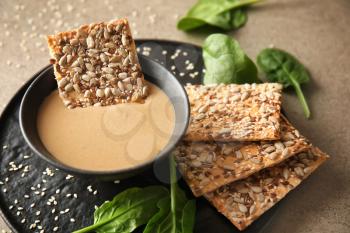 Bowl of tasty tahini with crackers on table�