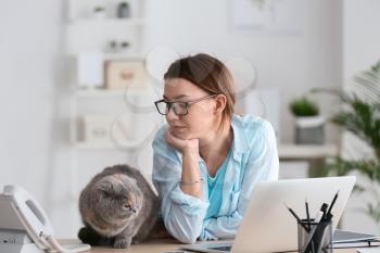 Young woman working with her cute cat in office�