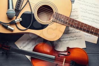 Guitar, violin and music sheets on table, top view�