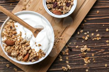 Bowl with tasty yogurt, oatmeal and almonds on wooden background�