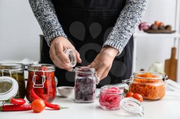 Woman preparing beetroot for fermentation at table in kitchen�