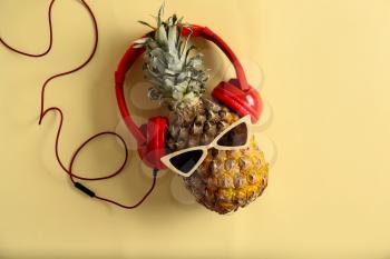 Funny pineapple with sunglasses and headphones on color background�