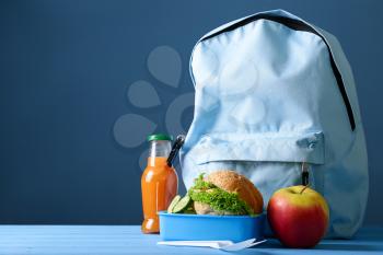 Schoolbag and lunch box with healthy food on table�