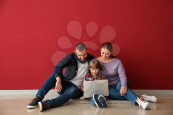 Happy family with laptop sitting on floor in their new flat�