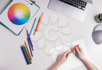 Female graphic designer with pencils, color palette and laptop on white background�