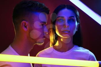 Portrait of young couple with neon lamps on dark background�