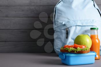 Schoolbag and lunch box with tasty food on table�