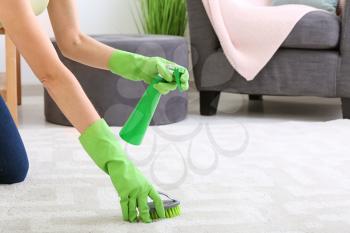 Young woman cleaning carpet at home�