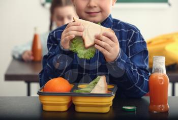 Little boy having school lunch in classroom�