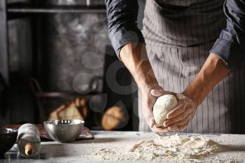 Young man preparing dough for bread in kitchen�