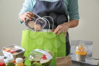 Worker of food delivery service packing order for customer�