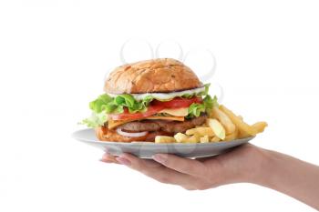Female hand holding plate with tasty burger and french fries on white background�