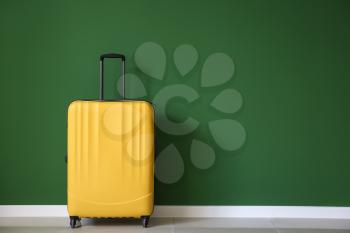 Packed suitcase near color wall�