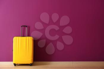 Packed suitcase near color wall�