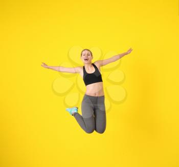 Young sporty woman jumping against color background�