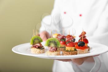 Chef holding plate with tasty canapes, closeup�