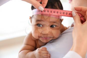 Pediatrician examining African-American baby in clinic�