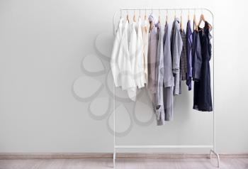 Rack with stylish clothes near light wall�