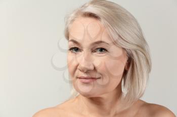 Mature woman with clear skin on light background�