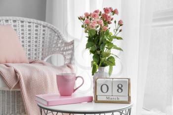 Bouquet of beautiful flowers, book, cup of coffee and calendar with date 8 MARCH on table. International Women's Day celebration�