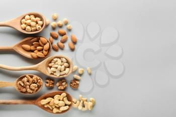 Spoons with different tasty nuts on light background�
