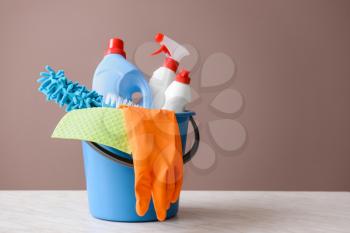 Set of cleaning supplies on table against color background�