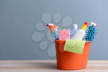 Set of cleaning supplies on table against color background�