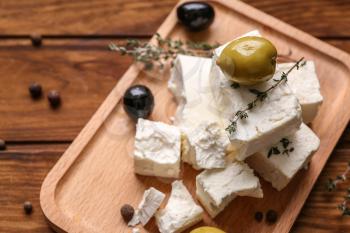 Plate with tasty feta cheese and olives on wooden table�